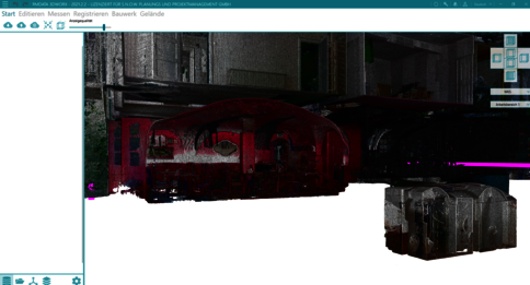 Dunkle 3D-Darstellung eines roten, ovalen Fahrzeugkörpers (Wagen/Tram) in einer Werkstattumgebung; rechts daneben liegt eine dunkle Kiste. Die Szene wirkt wie eine CAD-/3D-Softwareansicht mit Werkzeugleisten am Rand.