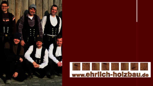 Group of men in traditional black vests and white shirts posing for a photo against a wooden backdrop; several wear hats. On the right, a maroon panel and a logo with wood-texture tiles and the site www.ehrlich-holzbau.de.