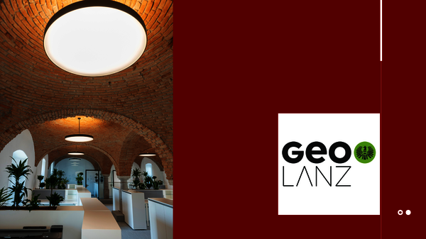 Innenraum eines Büros mit freigelegten roten Backsteinbögen, runden Deckenleuchten, weißen Arbeitsplätzen und Pflanzen; rechts ein maroonfarbener Bereich mit dem GEO LANZ-Logo in Weiß.