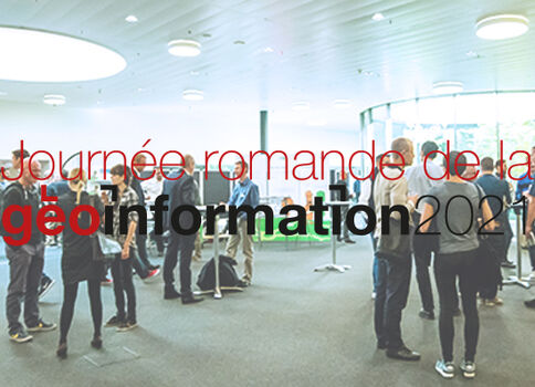 Plusieurs participants discutent dans un hall lumineux lors d'une journée professionnelle sur la géoinformation, avec des stands et des tables en arrière-plan.