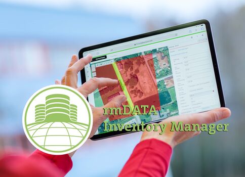 Eine Person hält ein Tablet mit einer kartengestützten Inventarverwaltungsoberfläche; auf dem Bildschirm sind farbige Kartenbereiche sichtbar. Über dem Tablet ist das Logo "lmDATA Inventory Manager" abgebildet.