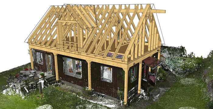 Partial view of a single-story house under construction, showing exposed wooden roof trusses and framing atop dark exterior walls, set in a grassy yard.