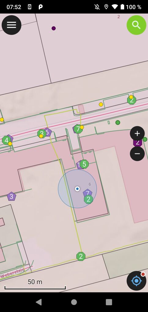 Eine Kartendarstellung eines Gebäudekomplexes mit vielen farbigen Markern in Kreisen; ein blaues Hervorhebungsfeld um ein Gebäude; unten ein Maßstab von 50 m; Randbedienlemente deuten auf Zoom- und Menüfunktionen.