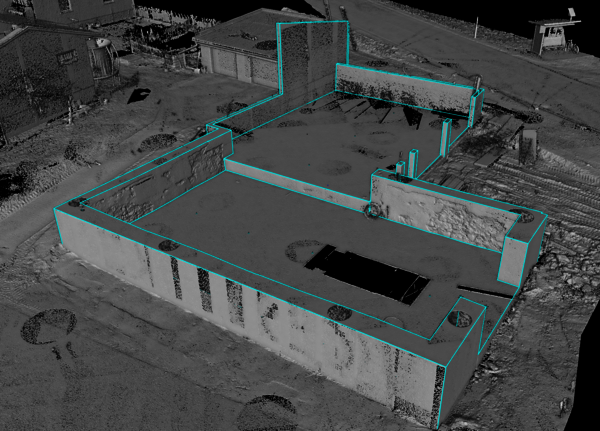 Vogelperspektive eines unfertigen Betonbaus mit Außenmauern und mehreren Innenwänden, die einen offenen Grundriss bilden. Blau markierte Linien umrissen die Wände des Gebäudes.