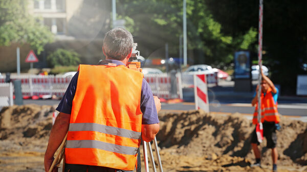 Vermesser am Messgerät auf einer Baustelle