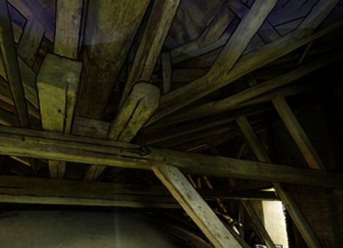 Dachboden mit einem dicht vernetzten Geflecht aus alten Holzbalken und Dachlatten, die kreuz und quer verlaufen. Staubige, dunkle Szenerie eines historischen Dachstuhls.