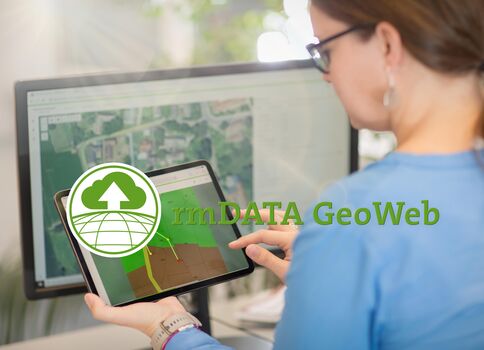 Une femme consulte une tablette affichant une carte géographique, tandis qu'un grand écran derrière elle montre aussi une carte.