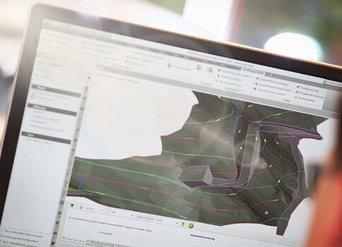 Computerbildschirm mit geöffneter CAD-/3D-Modellierungssoftware, die ein farbig konturiertes Oberflächen- oder Geländemodell zeigt.