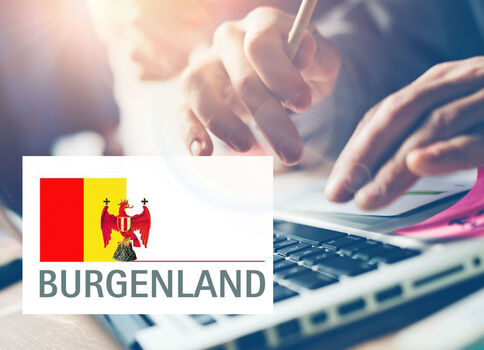 Nahaufnahme einer Person, die auf einer Laptop-Tastatur tippt; im Vordergrund ist ein Logo mit dem Burgenland-Wappen und dem Schriftzug Burgenland zu sehen.