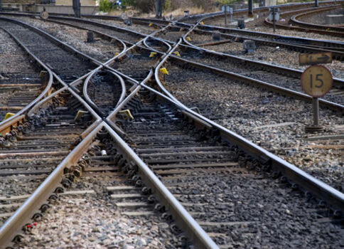 Mehrere Gleise kreuzen sich und verzweigen in einem Bahnbetriebsbereich; Weichen, Schienen und Schotter bilden ein dichtes Gleisnetz.