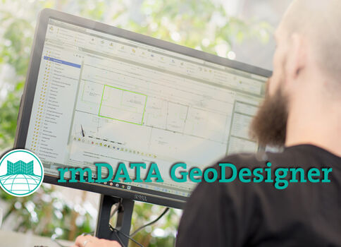 Ein Mann mit Bart sitzt vor einem Computerbildschirm, der GIS-Software mit Kartenansichten und Bearbeitungsfenstern zeigt; im Vordergrund ist das Logo rmDATA GeoDesigner sichtbar.