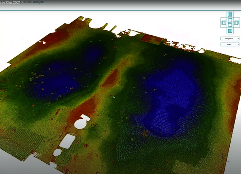 Eine 3D-Geländedarstellung mit farbkodierten Flächen: grüne Vegetationszonen, blaue Wasserflächen und bräunliche Bereiche; im Vordergrund zwei helle rechteckige Objekte.