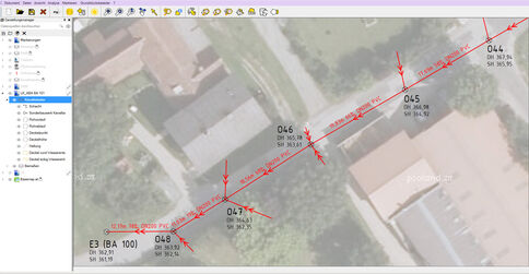 Satellitenaufnahme eines Wohnviertels mit einer roten Messlinie und Pfeilen, die eine Route entlang einer Straße markieren; dahinter Dächer, Gärten und weitere Straßen sind sichtbar.