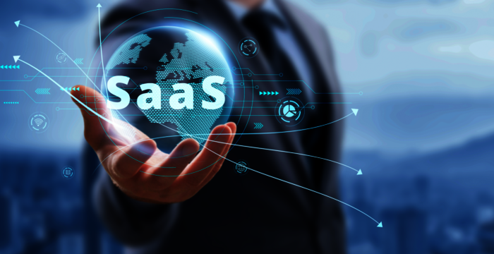 Eine Person im Anzug hält eine leuchtende holografische Globuskugel mit der Aufschrift „SaaS“, umgeben von digitalen Linien und Pfeilen – Darstellung von Cloud-Software bzw. Software as a Service.