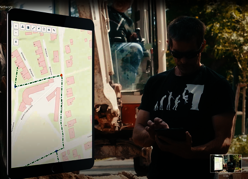 Auf einer Baustelle bedient ein Mann mit Sonnenbrille ein Smartphone; links zeigt ein Tablet eine Kartenansicht mit markierten Wegen, während ein Bagger im Hintergrund arbeitet.