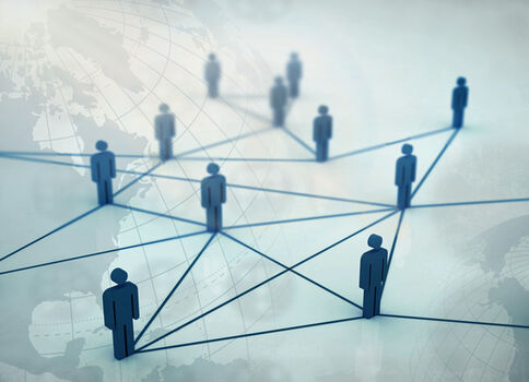 Mehrere blaue Figuren stehen auf einem abstrakten Netzwerk aus Linien, das sie global vernetzt; im Hintergrund ist eine verschwommene Weltkarte erkennbar.