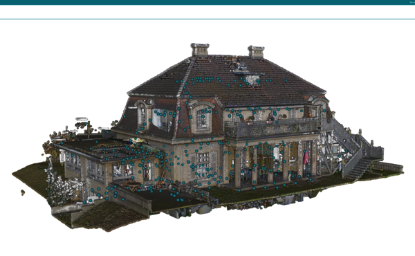 Two-story stone house with a steep, gabled roof, several chimneys, and a wraparound porch. Exterior stairs on the right lead to the entrance; the house sits in a landscaped yard.