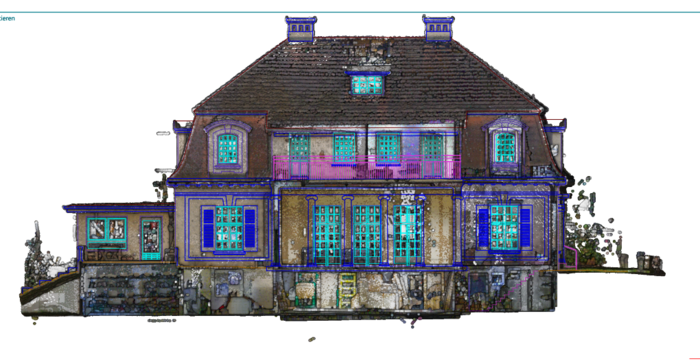 A large, decorative two-story house with a steep dark roof, several dormer windows, and bright blue window frames. The façade shows a central entry and a stone foundation, giving an ornate, symmetric residential building appearance.