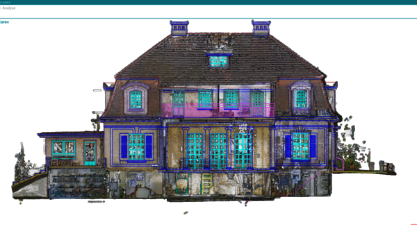 A large, decorative two-story house with a steep dark roof, several dormer windows, and bright blue window frames. The façade shows a central entry and a stone foundation, giving an ornate, symmetric residential building appearance.