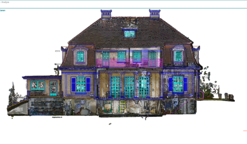 A large, decorative two-story house with a steep dark roof, several dormer windows, and bright blue window frames. The façade shows a central entry and a stone foundation, giving an ornate, symmetric residential building appearance.