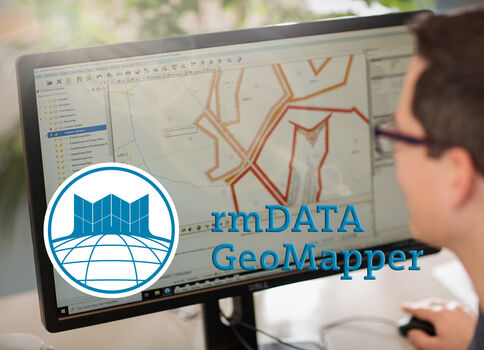 Personne utilisant un ordinateur montrant une application de cartographie géospatiale avec des tracés orange sur une carte; logo rmDATA GeoMapper au premier plan.