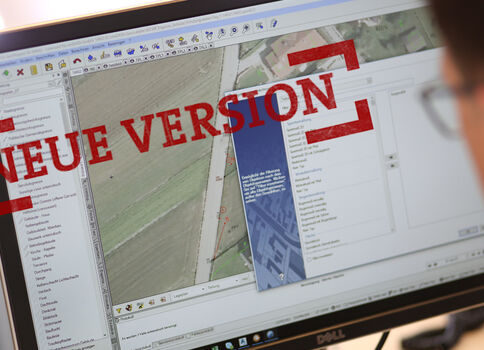 Computerbildschirm zeigt Kartenbearbeitungssoftware; auf dem Bildschirm ist eine Karte sichtbar und eine große rote Aufschrift NEUE VERSION darüber.