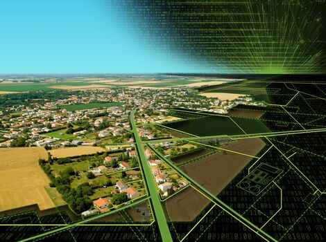 Luftaufnahme einer ländlichen Siedlung mit Feldern und einer Hauptstraße, die durch das Dorf führt. Rechts darüber liegt eine grün-schwarze digitale Netz- und Hexagon-Grafik, die Technologie oder Vernetzung symbolisiert.