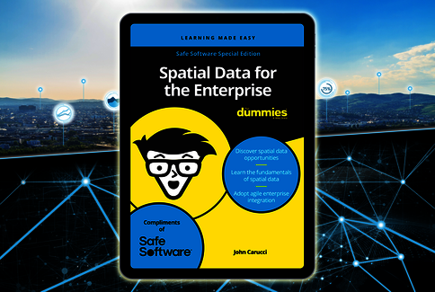 Ein Tablet zeigt das Buchcover “Spatial Data for the Enterprise for Dummies” von John Carucci. Gelbes Cover mit einer cartoonhaften Figur mit Brille. Hintergrund ist eine vernetzte Stadtlandschaft mit leuchtenden Netzlinien, Hinweis auf Geodaten und Unternehmensintegration.
