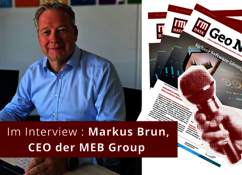 Ein Mann in einem hellblauen Hemd sitzt an einem Schreibtisch in einem Büro; er wird interviewt. Im Vordergrund ein roter Banner mit der Aufschrift 'Im Interview'. Im Hintergrund liegen Magazine.