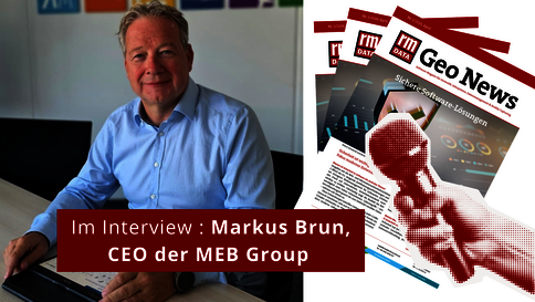 Ein Mann in einem hellblauen Hemd sitzt an einem Schreibtisch in einem Büro; er wird interviewt. Im Vordergrund ein roter Banner mit der Aufschrift 'Im Interview'. Im Hintergrund liegen Magazine.