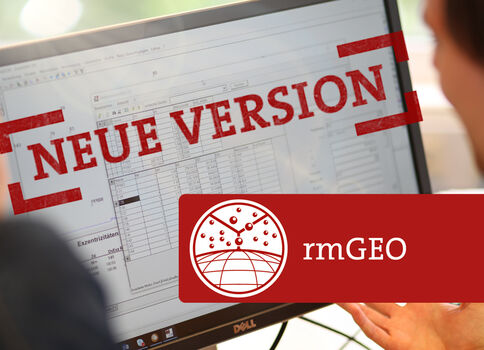 Zwei Personen beobachten einen Computerbildschirm, auf dem deutlich NEUE VERSION in roter Stempelgrafik erscheint. Darüber liegt ein rotes rmGEO-Logo-Banner, als Hinweis auf eine neue Softwareversion.