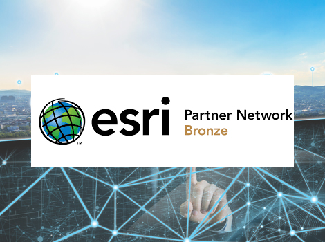 Weiße Bannerfläche mit dem Esri-Logo (Globus neben dem Schriftzug esri) und der Bezeichnung 'Partner Network Bronze', vor hellem Stadtpanorama mit leuchtenden Netzlinien im Hintergrund.