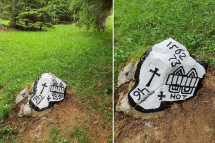 Zweierlei Ansichten eines im Gras liegenden Steins im Park; darauf befindet sich eine Kreuzdarstellung neben einer kleinen Kirchen-Skizze mit Türmen, umgeben von Bäumen.
